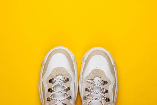 Μοντέρνα αθλητικά παπούτσια σε κίτρινο φόντο. Στο πάνω μέρος. Ελαχιστοποίηση - Φωτογραφία, εικόνα
