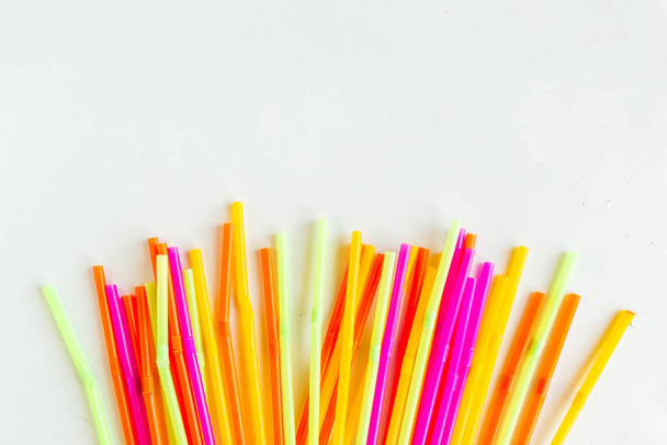 Multicolored plastic drinking cocktail straws on white background, top view. Make a cocktail.  - Photo, Image