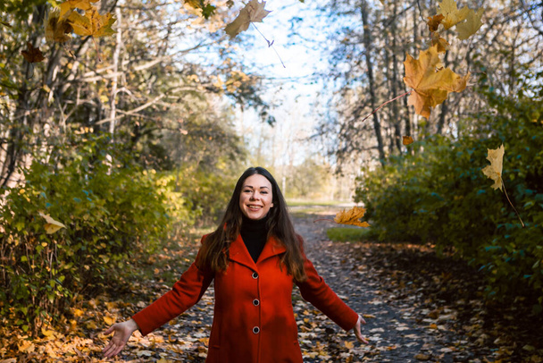 Beautiful young woman walking through an autumn park, fall background - Photo, Image