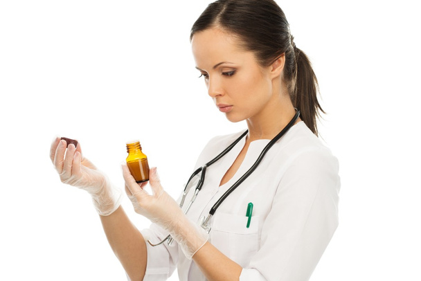Young positive brunette doctor woman reading prescription on a vial  - Fotó, kép