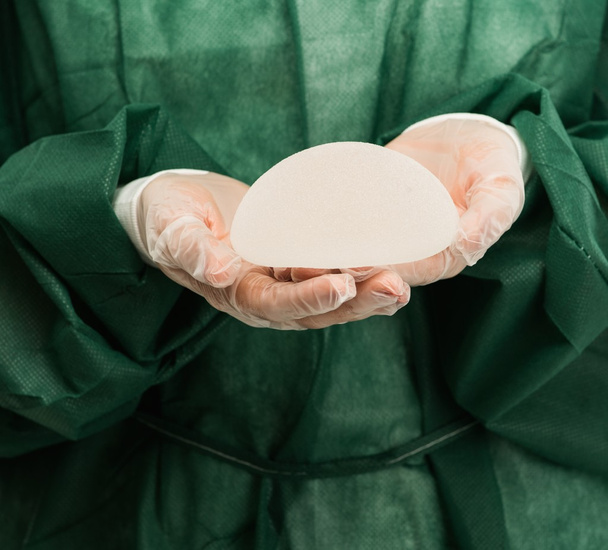 Mani di chirurgo plastico che tengono protesi mammarie al silicio
  - Foto, immagini