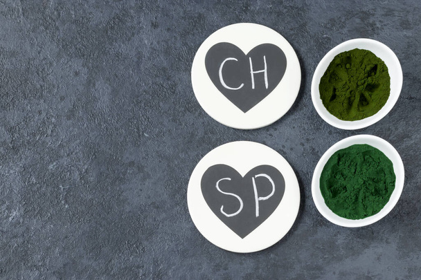 Chlorella a spirulina prášek na tmavém pozadí. Zelené superjídlo pro vegetariánskou stravu. Křídový nápis. Zdravý životní styl. Kopírovat prostor - Fotografie, Obrázek