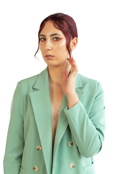 retrato de una joven con el pelo rojo con maquillaje y en una chaqueta verde y jtns en el estudio, moda de belleza - Foto, Imagen