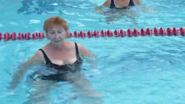 Stará dáma trénuje aqua gymnastiku v bazénu. - Záběry, video