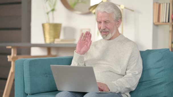 Videollamada en línea en el ordenador portátil por el anciano mayor en el sofá  - Metraje, vídeo