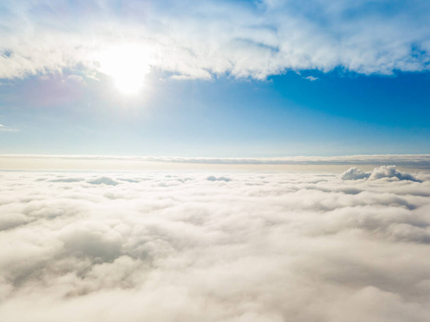 Вид с воздуха. Летающие над белыми облаками днем в солнечную погоду. - Фото, изображение