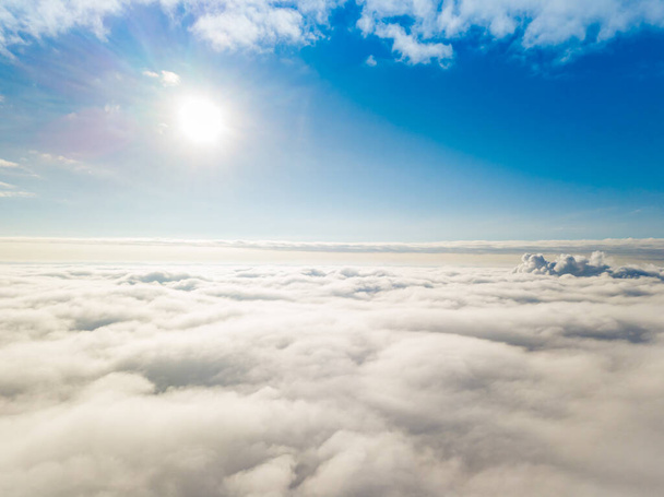 Légi felvétel. Napközben fehér felhők fölött repül napsütésben. - Fotó, kép