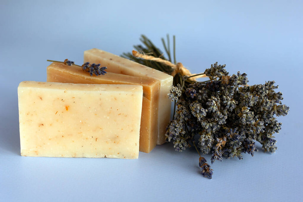 Natural handmade soap and a bouquet of dried lavender on a blue background. The concept of body care. Spa organic cosmetics. Copy space. - Photo, Image