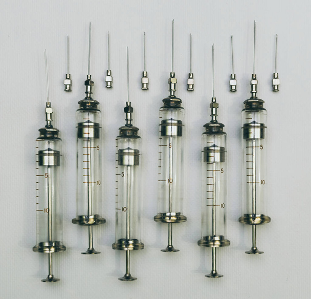Treatment and healthcare. Old fashioned glass injection syringe on sterile clean white background - Foto, Imagem