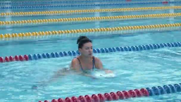 Yüzme havuzunda stiroköpük halterli su jimnastiği eğitimi alan bir kadın.. - Video, Çekim