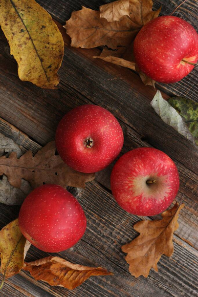 テーブルの上に赤いリンゴと秋の葉をジューシーに - 写真・画像