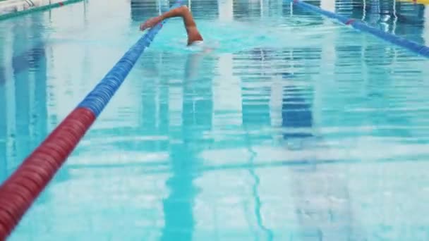 Professionele zwemmer nauwelijks uit te werken in het overdekte zwembad zwemmen over de baan. - Video