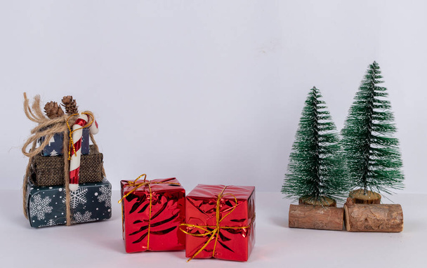 A close-up of Christmas decorations, with several gifts in different boxes, two trees with a white background. - Foto, Imagem