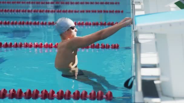 Vue latérale du nageur professionnel masculin réchauffe son corps dans la piscine avant de nager - Séquence, vidéo