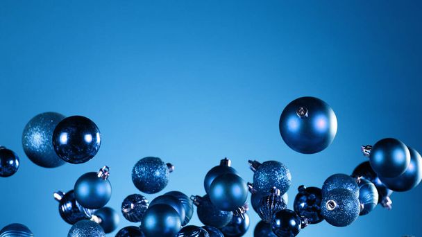 Flying christmas balls on coloured background, concept of celebrating, studio shot. - Foto, imagen