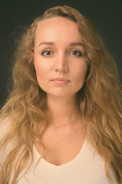 Молодая красивая женщина с длинными волнистыми светлыми волосами на сером фоне - Фото, изображение