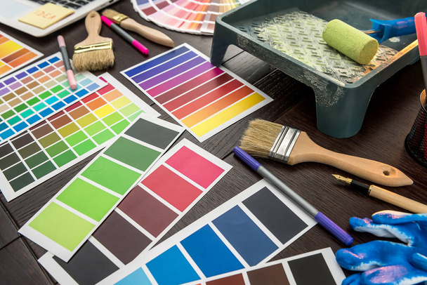Набор инструментов для покраски как руководство по палитре цветной бумаги, синие перчатки и кисть на деревянной доске. Концепция строительства и реконструкции - Фото, изображение