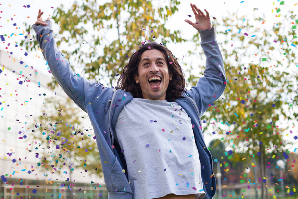 νεαρός άνδρας διασκεδάζει γιορτάζοντας με κομφετί εξωτερική - Φωτογραφία, εικόνα