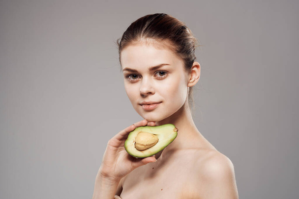 Beautiful brunette naked shoulders avocado in clean skin hand - 写真・画像