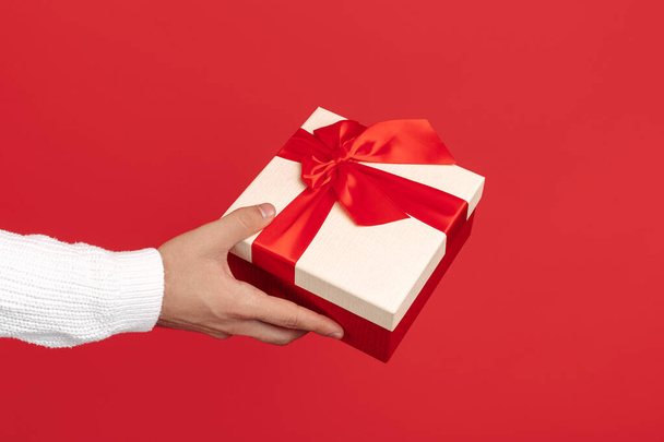 Close-up image of man hands holding gift box over red background. Christmas and New Year concept. - Foto, Imagem
