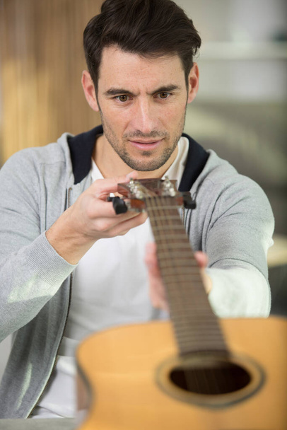 man guitarist checks guitar musical instrument - Φωτογραφία, εικόνα