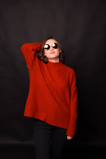 A portrait of a young woman in sweater with sun glasses posing in front of camera - Photo, Image