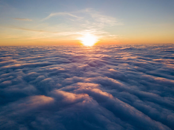 Закат над кудрявыми облаками, воздушный полет. Последние лучи солнца сияют на облаках. - Фото, изображение