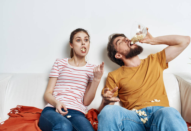 Man eet popcorn en mooie vrouw in een lichte kamer familie vrienden communicatio - Foto, afbeelding