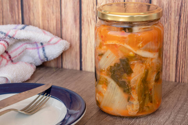 Kimchi kaali Jar, tyypillinen mausteinen korealainen ruoka maalaismainen ympäristössä valmis palvelemaan lautasella. - Valokuva, kuva