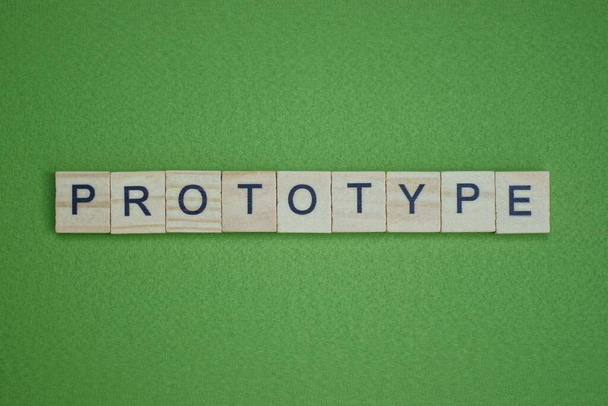 gray word prototype made of wooden square letters on green background - 写真・画像
