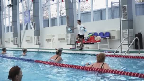 Instructor training women aqua gymnastic in swimming pool. - Footage, Video