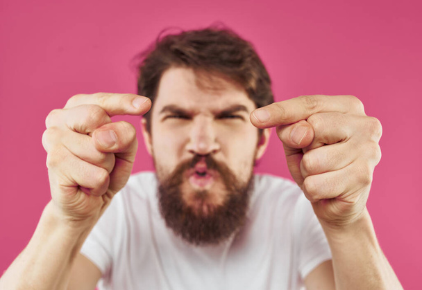 mies osoittaa peukalo sivulle vaaleanpunainen tausta stressi ärtyneisyys - Valokuva, kuva