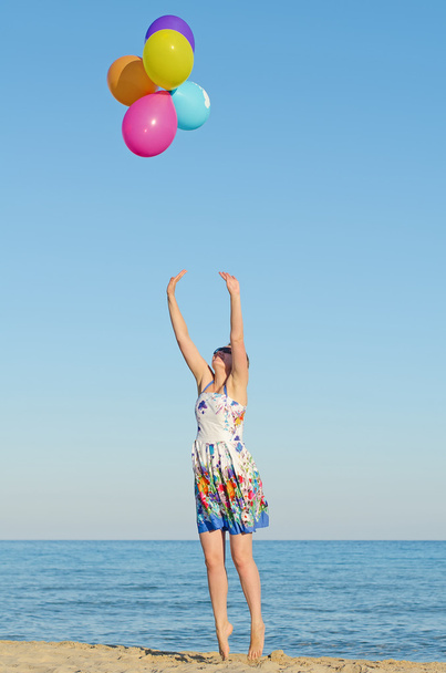 νεαρή γυναίκα με πολύχρωμα μπαλόνια πάνω από τη θάλασσα. - Φωτογραφία, εικόνα