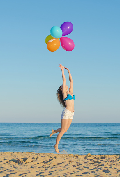 Женщина с цветными воздушными шарами над морем
. - Фото, изображение