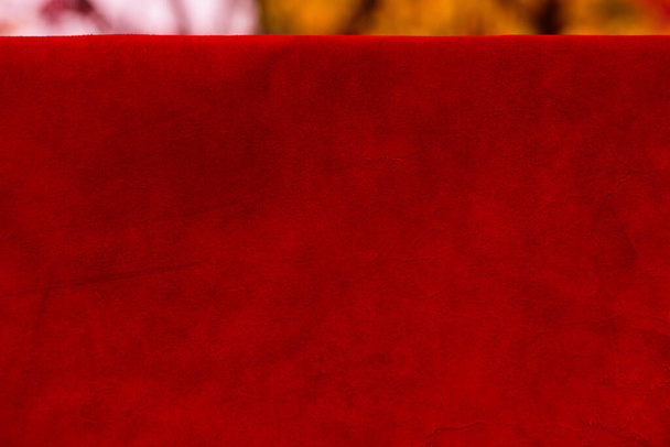Red matte background of suede fabric, closeup. Velvet texture of seamless leather. Felt material macro. Red suede texture. Fabric, leather, material for designers. - Foto, Imagen