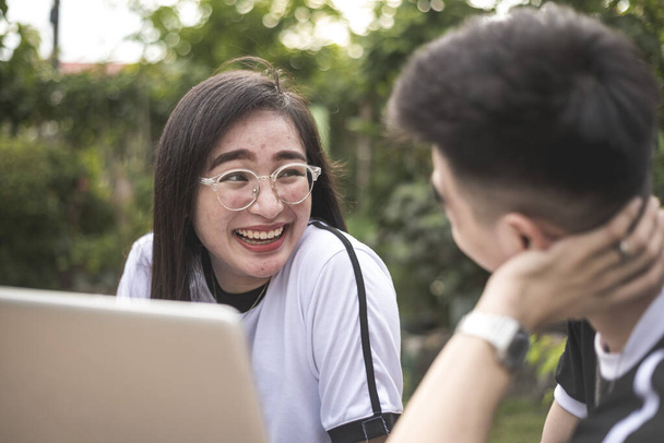 Une adolescente philippine sourit tout en conversant avec son petit ami lors d'une revue sur l'ordinateur portable à l'extérieur. - Photo, image
