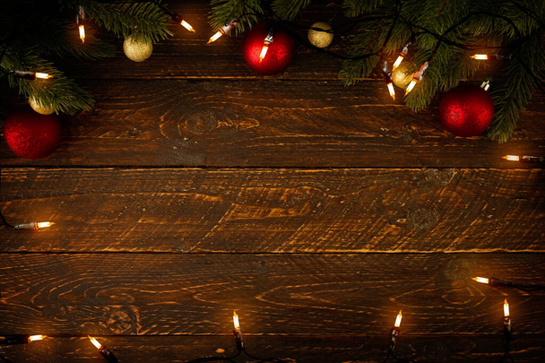 Christmas background - Christmas lights bulb and pine leaves decoration on wood plank, frame border design. Merry Christmas and New Year holiday background. top view. - Photo, Image