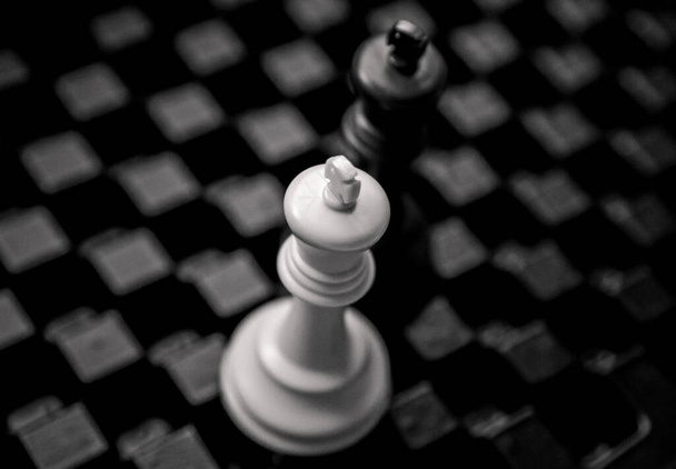 Mesa de ajedrez oscura con piezas de ajedrez en blanco y negro en concepto de primer plano. - Foto, imagen