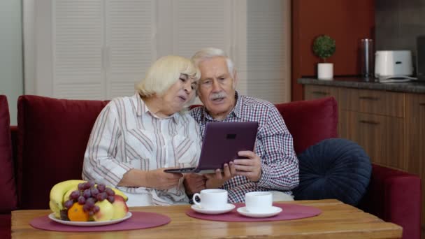 Οι πρεσβύτεροι παππούδες μιλάνε και χρησιμοποιούν ψηφιακό φορητό υπολογιστή στο σπίτι. Κλείδωμα του ιού του κερατοειδούς - Πλάνα, βίντεο