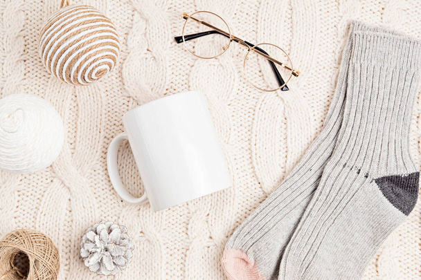 Mockup with white mug and eco friendly Christmas ornaments on knitted background. Assortment of cozy hygge Xmas decorations with copy space for text on blank cup. Flat lay, top view - Photo, Image