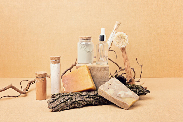 天然の血清、乾燥石鹸、砂ベージュの背景に木の破片が表示される粘土マスク。中性色の自然環境で有機環境に優しいスパの美容製品のプレゼンテーション  - 写真・画像