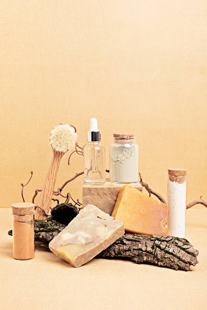 Natural serum, dry soap and clay masks displayed with pieces of wood on sand beige background. Presentation of organic eco friendly spa beauty products in neutral colors nature environment  - Photo, Image