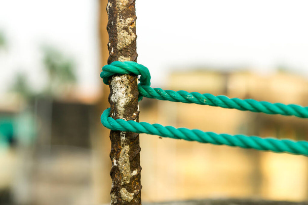 A rope is tied in a knot around a fence post, rope tied Hitch Knots on a rusty iron pole isolated from background. - Photo, Image