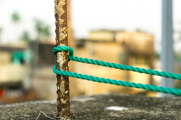 A rope is tied in a knot around a fence post, rope tied Hitch Knots on a rusty iron pole isolated from background. - Photo, Image