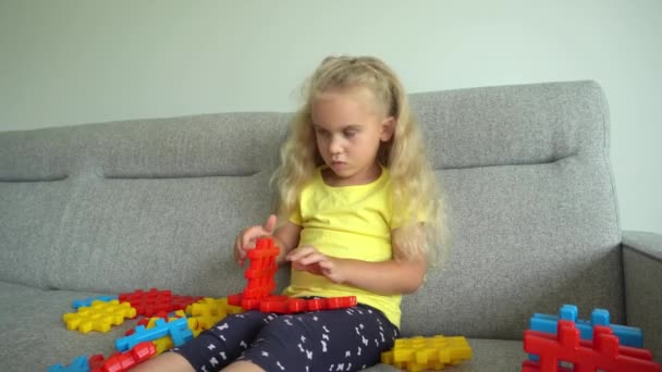 Designer fêmea criança brincar com grandes blocos de ligação no sofá. Movimento de Gimbal - Filmagem, Vídeo