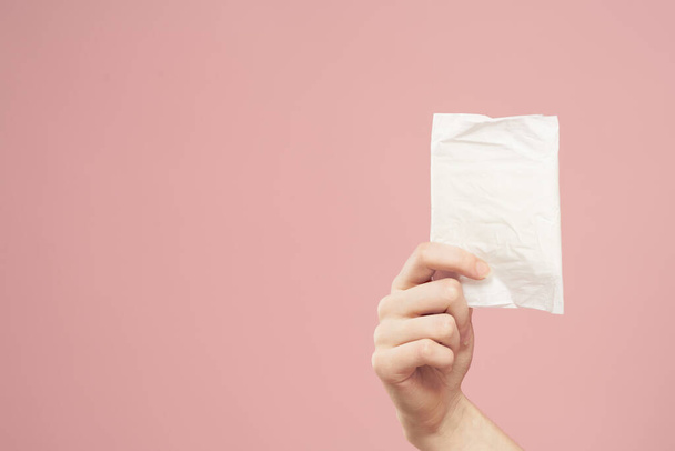 Leggen in verpakking in vrouwelijke handen op een roze achtergrond bijgesneden uitzicht hygiëne schoon uiterlijk - Foto, afbeelding