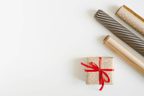 Idea de regalo de Navidad. Caja de regalo con cinta roja y rollos de papel kraft. DIY eco amigable regalo envoltura  - Foto, imagen