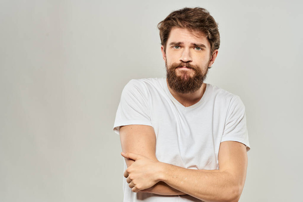 Mann im weißen T-Shirt gestikuliert mit den Händen Studio Unzufriedenheit Lifestyle Licht Hintergrund - Foto, Bild