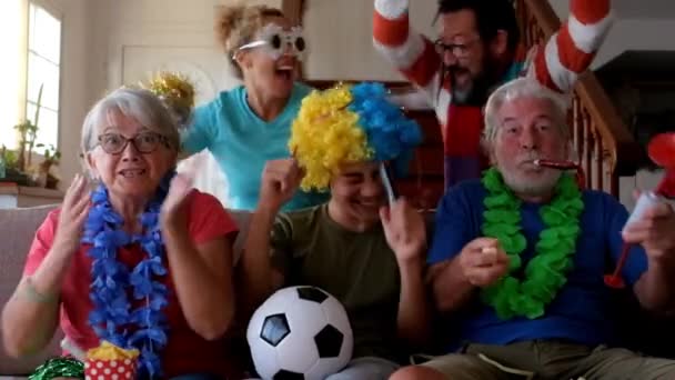 viileä perhe hauskoissa puvuissa katsomassa jalkapallopeliä ja tukitiimiä - Materiaali, video