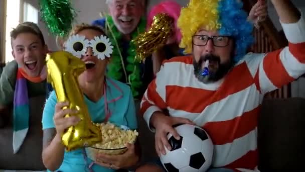 Coole Familie in lustigen Kostümen schaut Fußballspiel und Begleitteam zu - Filmmaterial, Video